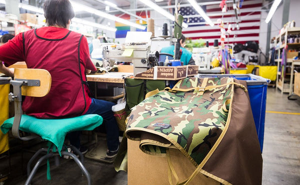 A TOM BIHN crew member sitting at her sewing machine, next to a Beaver Transfer Bag in process of being made